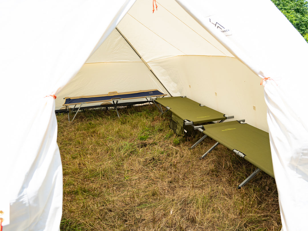 Camping tent with two cot beds inside on a grassy outdoor setting