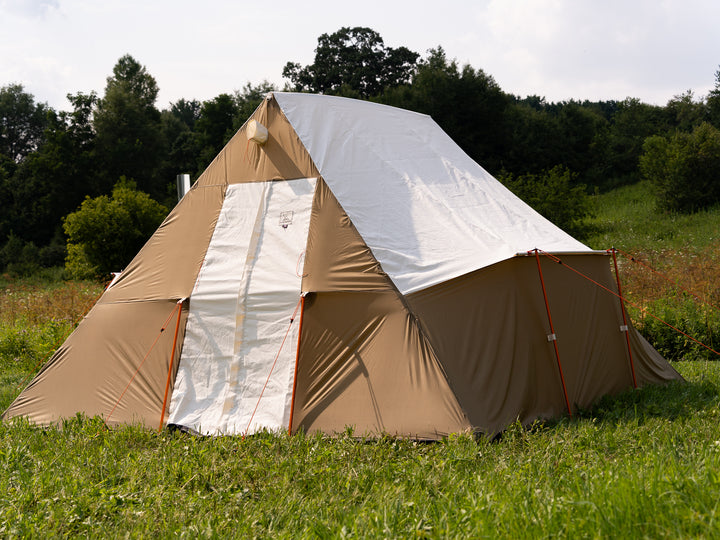 Beige and white canvas tent in a grassy field with trees in the background
