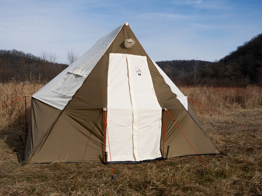 Beige and white tent in a field 