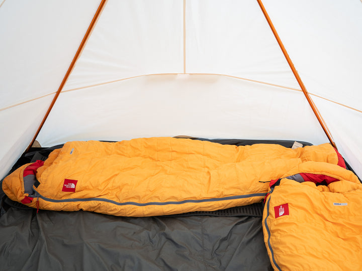 Yellow sleeping bag inside a tent with visible brand logo.