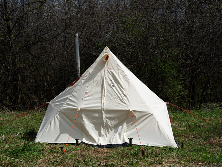 White tent set up in a grassy area with trees in the background