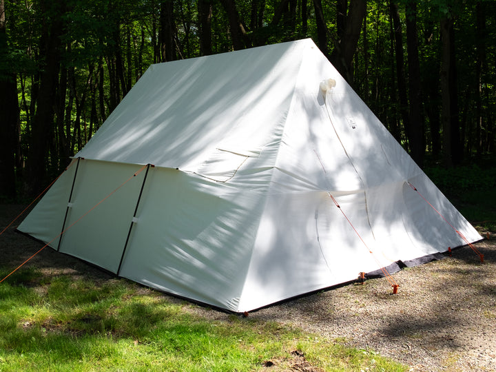 Snowtrekker 18x18 Mega Crew Setup on gravel with door closed and stove jack cover over stove pipe exit trees in background in Pennsylvania 