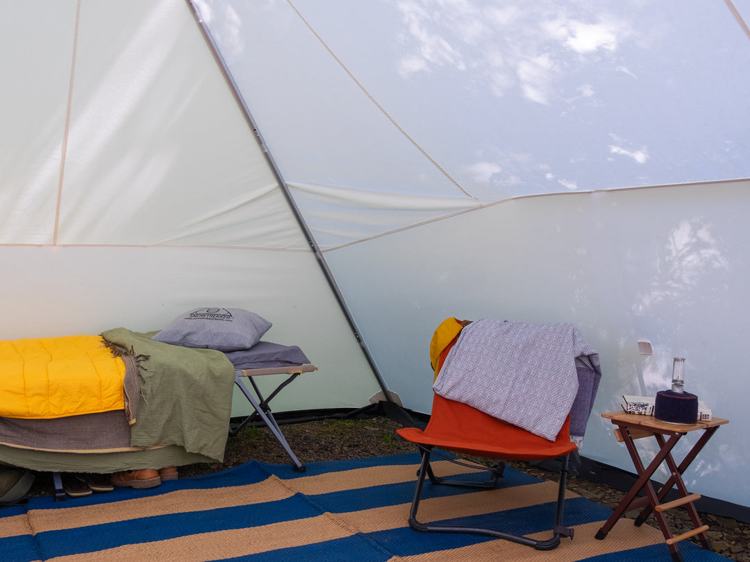 Snowtrekker 13x18 Mega Crew Inside Tent With Cot along backwall and Chair to right of cot with small end table next to chair with gas lamp on end table 