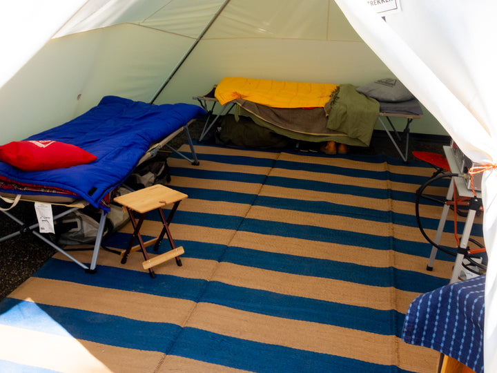 Snowtrekker 13x18 Mega Crew looking Inside Tent through open door With two cots one setup along left sidewall and one setup along rear wall cook stove partially visible on right sidewall