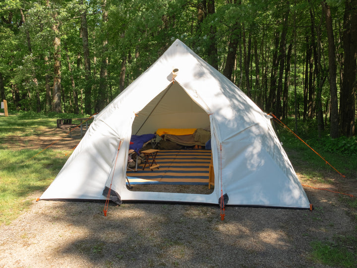 Snowtrekker 13x18 Mega Crew Open Doo setup in Pennsylvania campground cot along left side and rear wall visibile through open door with picnic table fire ring and trees in background