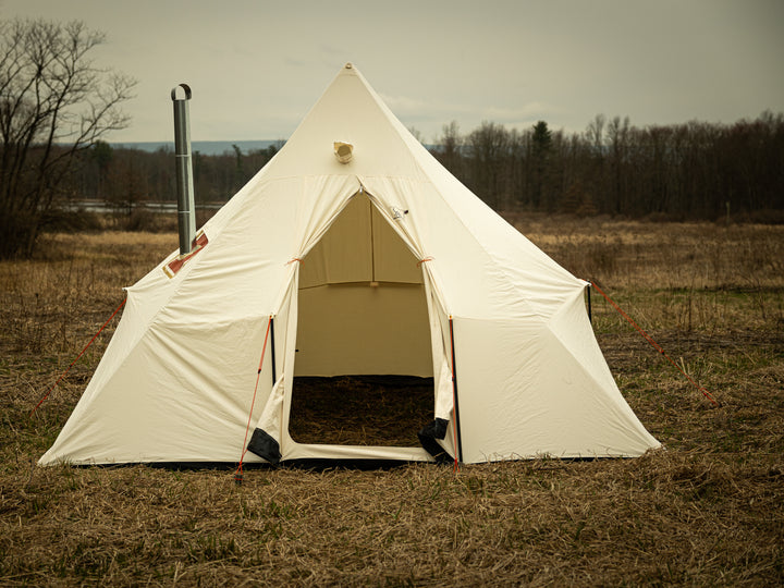 Snowtrekker 13x13 Mega Crew setup door tied open with stove pipe vertically exiting the tent on the left side with woods and pond in background