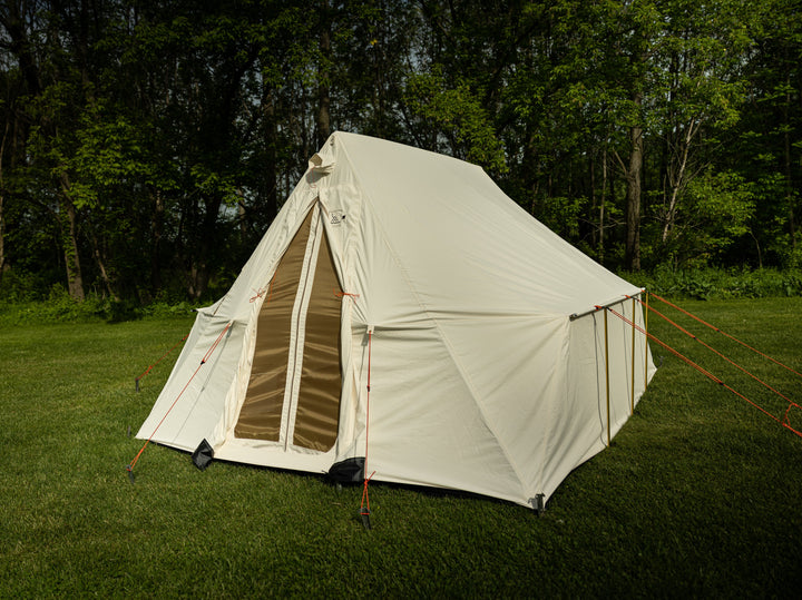 Snowtrekker 10x13 Outfitter front of tent with canvas door open screen door closed setup in green grass with trees in background