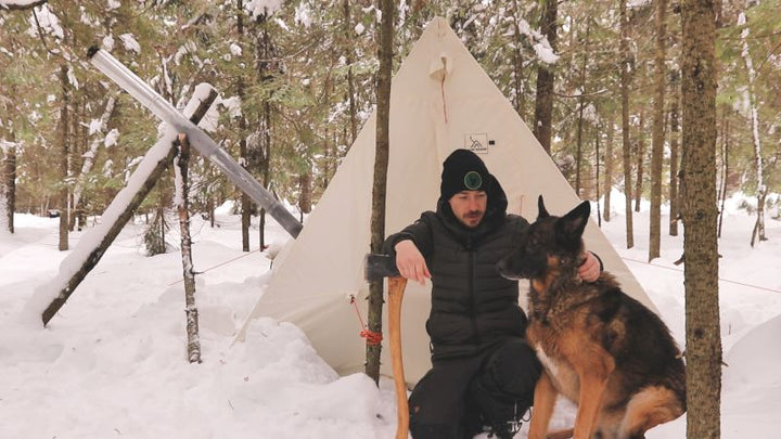 Joe Robinet and his dog outside a Snowtrekker Tent in the snowy woods