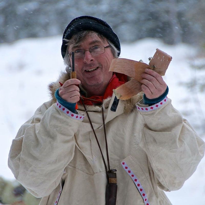 Kevin Callan in a winter coat holding birch bark and a firestarter rod