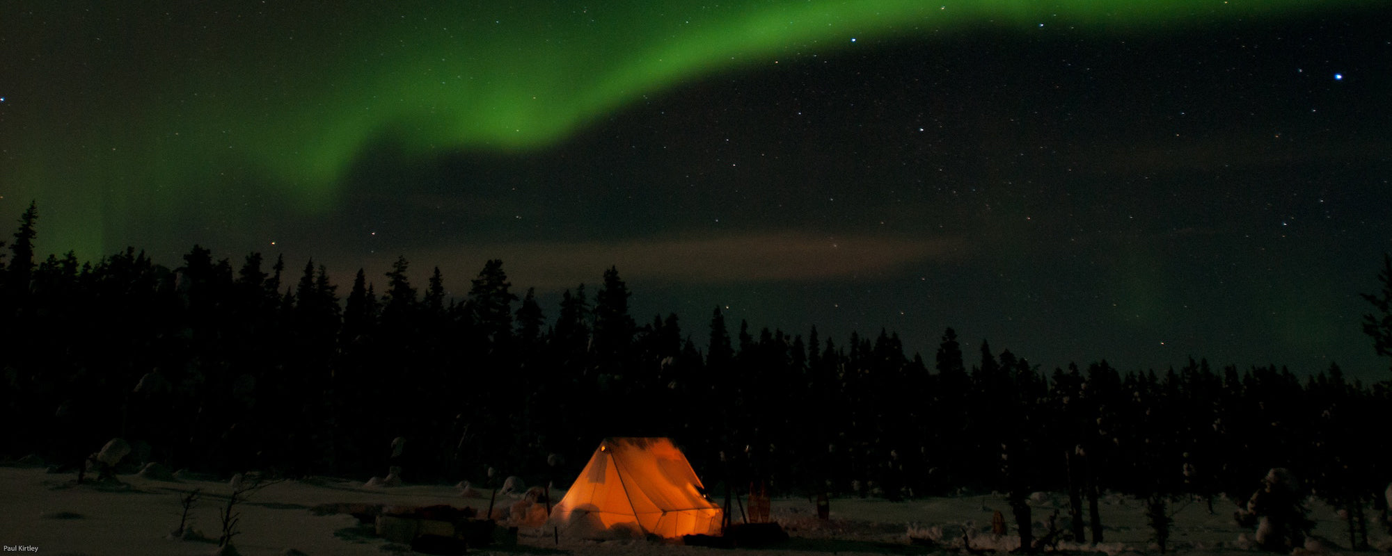 night camping scene with lit tent and northern lights above