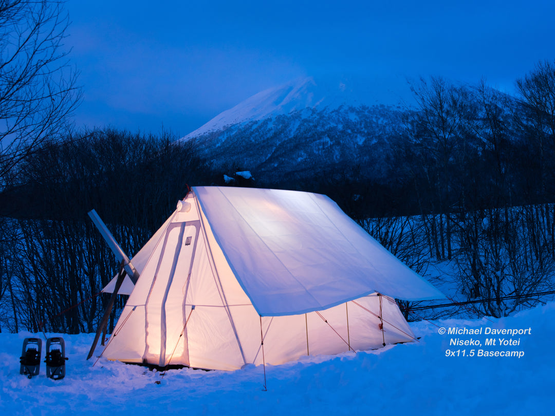 Snowtrekker 9x11.5 Basecamp Tent With Fly setup in snow with trees and snow covered mountain in background