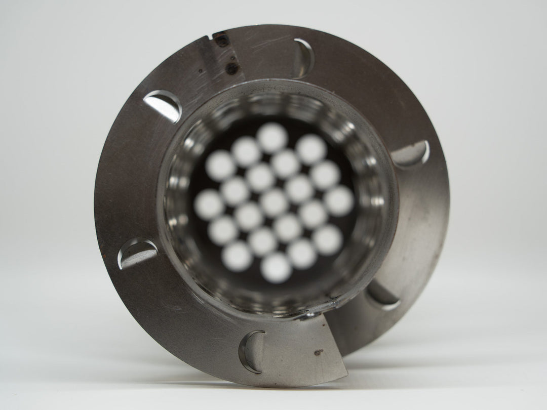 Metallic component with white spherical objects inside on a gray background