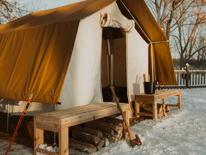 Brown tent with wooden benches and tools in a snowy outdoor setting