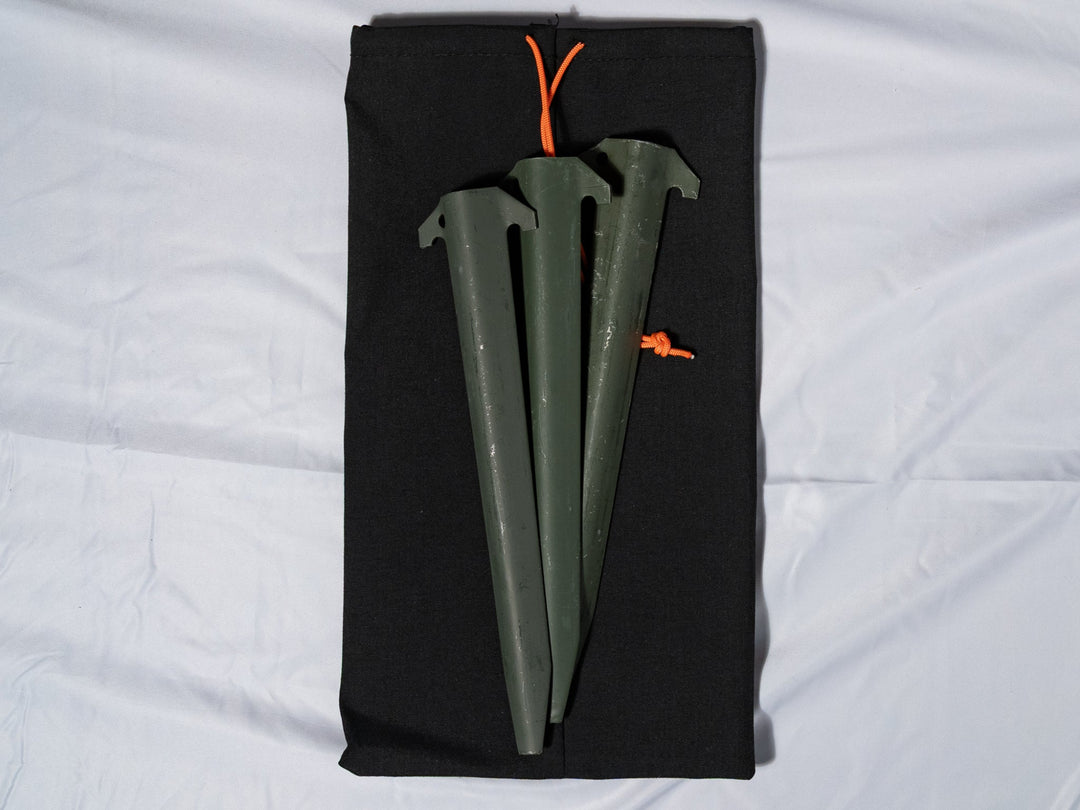 Three green tent stakes in a black carrying case on a white background