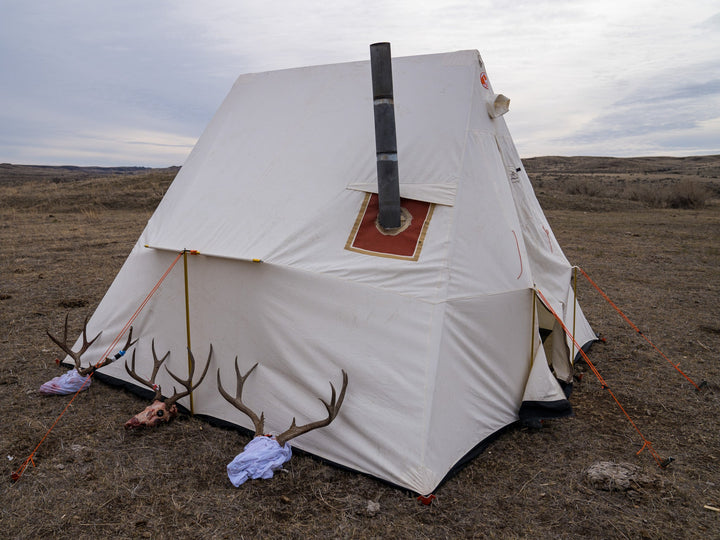 White canvas tent with a chimney in a barren landscape